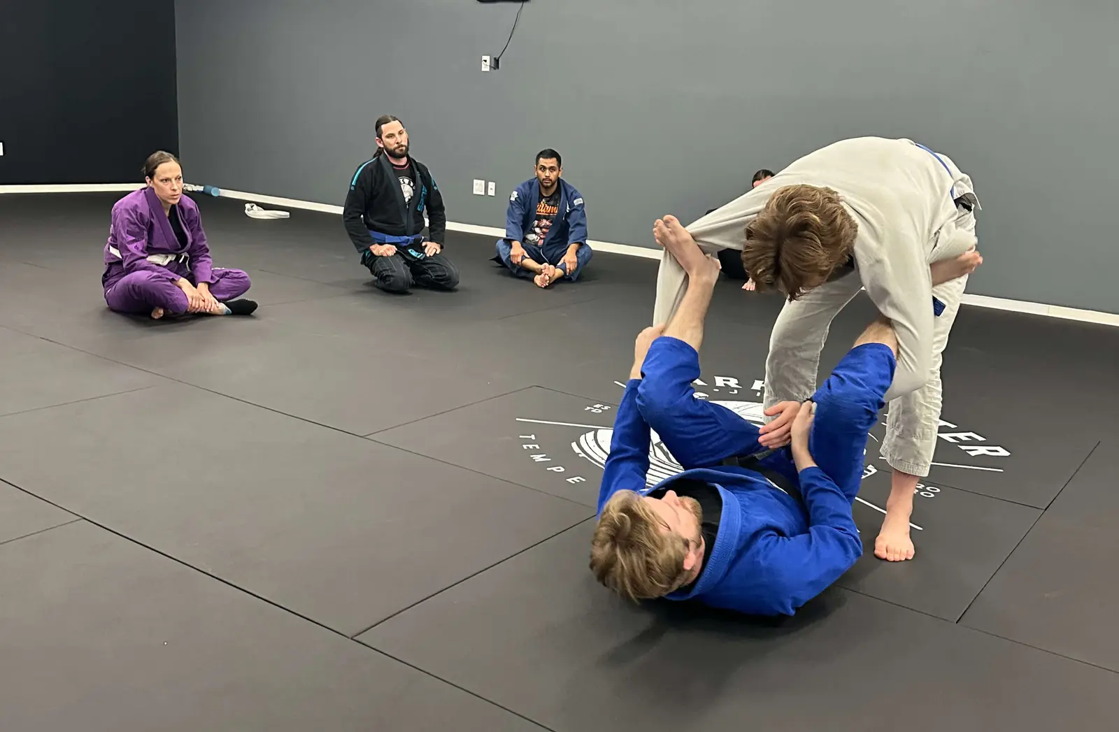 Adult gi rolling during BJJ class at Dark Matter Jiu-Jitsu Tempe AZ
