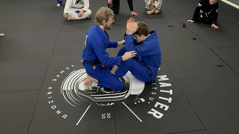 Coach Korey demonstrating a jiu-jitsu technique with a student during class at Dark Matter Jiu-Jitsu in Tempe